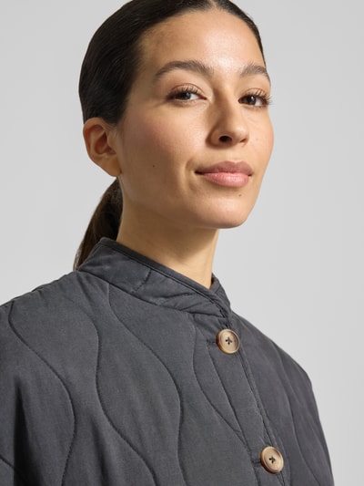 Frauenmodel trägt Steppjacke aus Lyocell-Baumwoll-Mix mit Stehkragen von Jake*s Casual in Dunkelgrau, große Knöpfe, Nahaufnahme Oberkörper. Regular Fit, sichtbare Steppnähte, glatte Textur.