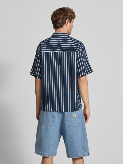 Männermodel trägt Regular Fit Freizeithemd mit Reverskragen Modell 'HOWIE' von Redefined Rebel, dunkelblau-weiß gestreift, Allover-Look, Reine Baumwolle, Label-Detail, Rückenlänge bei Größe M 60 cm, Schulterbreite 60 cm, Ärmellänge 30 cm, Ganzkörperansicht Rückansicht.