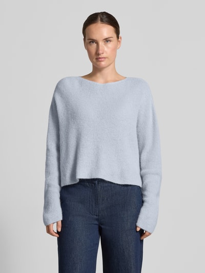 Frauenmodel trägt Oversized Wollpullover aus Alpaka-Mix von DRYKORN in Hellblau, Ripp-Optik, weite Schultern, Ganzkörperansicht von vorne.