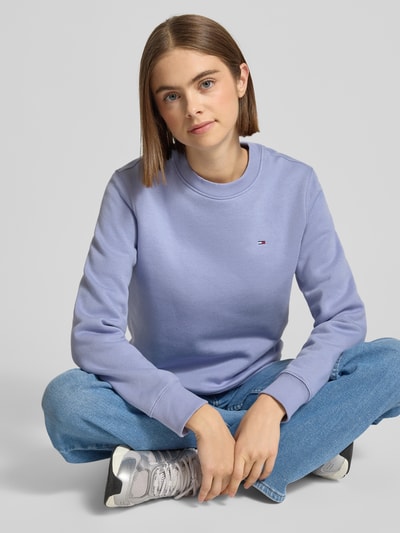 Modelka kobieca nosi Regular Fit Sweatshirt aus Baumwoll-Mix od Tommy Jeans, jasnofioletowy, gładki, logo, okrągły dekolt, długi rękaw, ujęcie całej sylwetki z przodu.