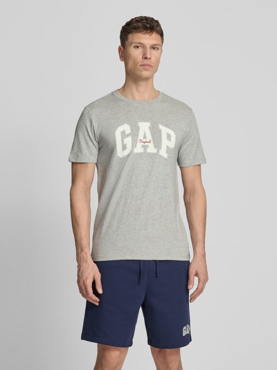 Männermodel trägt T-Shirt mit Logo und Rundhalsausschnitt von GAP, Herren T-Shirt aus Reine Baumwolle, Regular-Fit, Grau, Ganzkörperansicht von vorne. Rückenlänge bei Größe M: 69 cm