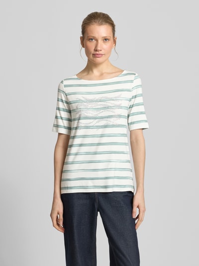 Kobiece model prezentuje T-Shirt aus Viskose-Elasthan-Mix mit Ziersteinbesatz von Betty Barclay, krój regular fit, półokrągły dekolt, półrękaw, długość pleców w rozmiarze 36: 61 cm, jasnoniebieskie paski, przód z aplikacją z dżetów, widok całej sylwetki od przodu.