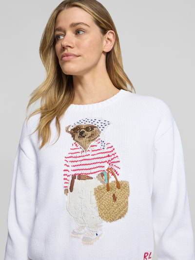 Kobiece model nosi Regular Fit Strickpullover aus Baumwoll-Leinen-Mix mit Bear Intarsien od Polo Ralph Lauren, efekt: jednolity kolor, aplikacja: motyw niedźwiedzia, kształt kołnierza: okrągły dekolt, rękaw: krótki rękaw, zakończenie rękawów: prążkowane, wykończenie materiału: dzianina, materiał: mieszanka bawełny i lnu, widok: zbliżenie na górną część ciała.