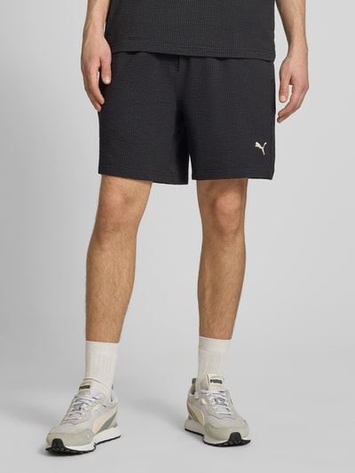 Männermodel trägt Shorts mit Logo-Stitching von PUMA PERFORMANCE aus Reine Baumwolle mit Strukturmuster, Gerader-Schnitt, Ganzkörperansicht von vorne.