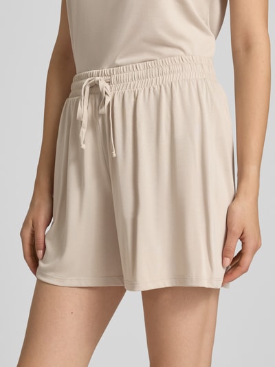 Kobieta nosi Relaxed Fit Stoffshorts aus Viskose-Mix Modell 'ANORA' od PIECES, jasny beż, gładka tekstura, zbliżenie na biodra, Damen Stoffshorts.