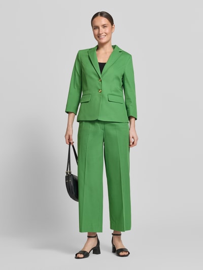 Frauenmodel trägt Wide Leg Hose aus Viskose-Mix mit Bügelfalten von More & More in kräftigem Grün, glatte Struktur, Ganzkörperansicht von vorne. Kontext: Damen Hose mit Baumwoll-Anteil, Bügelfalten, Knopf- und Reißverschluss, Bundweite 39 cm, Innenbeinlänge 66 cm.