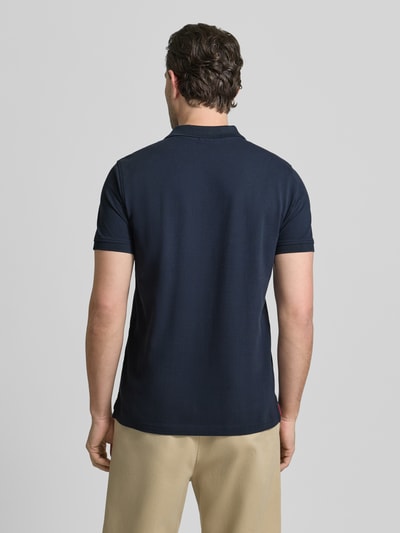 Männermodel trägt Slim Fit Poloshirt mit Logo-Stitching von MCNEAL in Dunkelblau, reine Baumwolle, Rückansicht, Ganzkörperansicht Rückansicht.