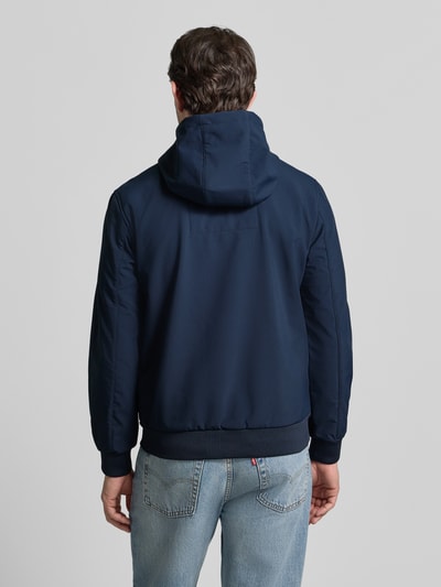 Männermodel trägt Regular Fit Funktionsjacke mit Kapuze von Tom Tailor Denim in Dunkelblau, elastische Abschlüsse, wasserfest, Rückenansicht.