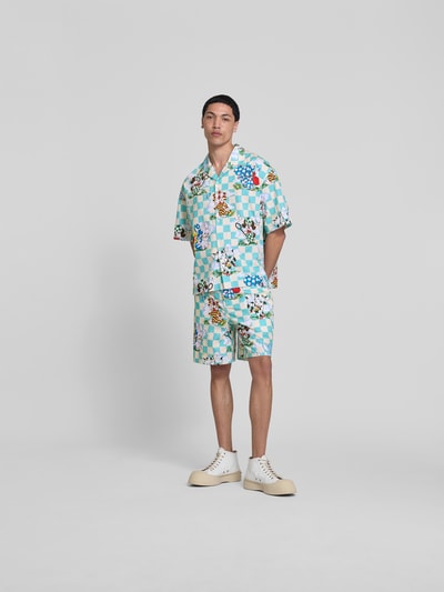 Mannenmodel draagt Shorts met Allover-Motiv-Print van Kenzo, puur katoen, relaxed fit, elastische band, knoop- en ritssluiting, all-over motiefprint in turquoise, wit en bruin, binnenbeenlengte maat M 41 cm, bandwijdte maat M 18 cm, Ganzkörperansicht von vorne.