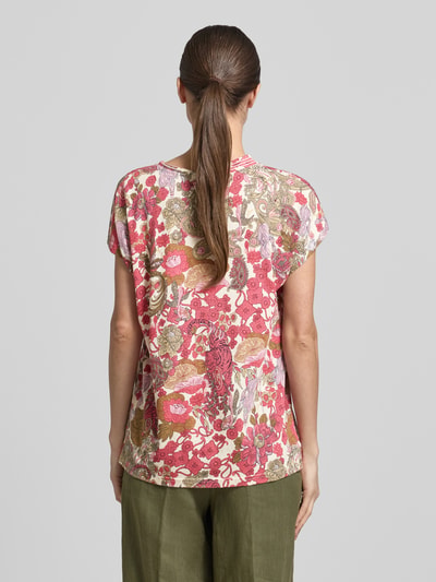 Männermodel trägt Regular Fit T-Shirt aus Viskose-Mix Modell 'Felicity' von Soyaconcept, floraler Allover-Print, krój regular fit, V-Ausschnitt, odzież damska, bogate odcienie różu, zieleni i beżu, powierzchnia miękka, Ganzkörperansicht Rückansicht.