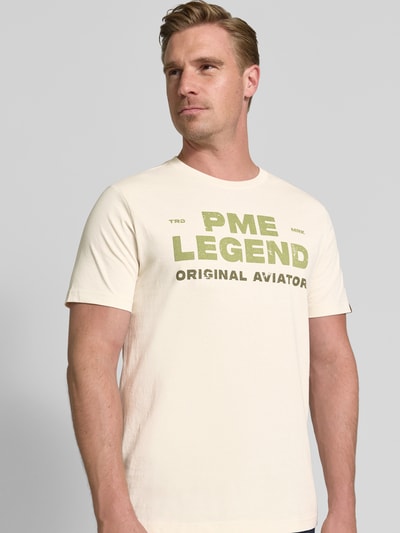 Männermodel trägt T-Shirt mit Rundhalsausschnitt und Label-Print von PME Legend in crème met groene labelprint, puur katoen, regular fit, ruglengte bij maat M 64 cm, Nahaufnahme Oberkörper.