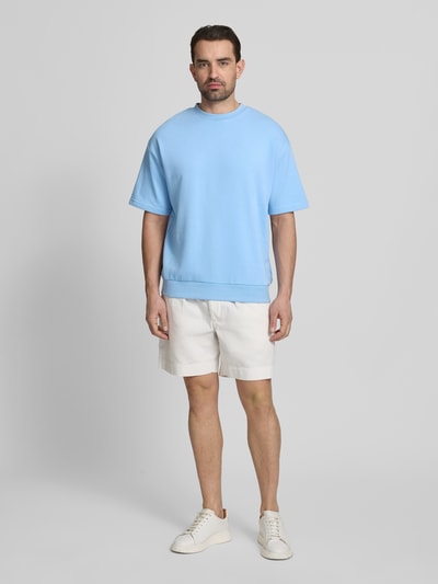 Männermodel trägt Oversized T-Shirt mit Rundhalsausschnitt von Lindbergh in Hellblau aus Baumwoll-Mix, Label-Detail, Ganzkörperansicht von vorne. Rückenlänge bei Größe M: 70 cm.