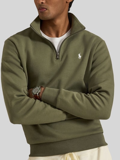 Männermodel trägt Relaxed Fit Troyer aus Baumwoll-Mix von Polo Ralph Lauren in Olivgrün mit sichtbarer Logo-Stickerei, Nahaufnahme Oberkörper. Herren Troyer von Polo Ralph Lauren.