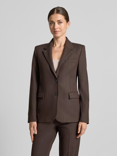 Frauenmodel trägt Regular Fit Blazer mit Viskose-Anteil Modell 'Bergen' von MANGO in Braun mit feiner Struktur, Ganzkörperansicht von vorne. Elastischer Material-Mix, Reverskragen, Pattentaschen, 2-Knopfleiste, glatte Textur.