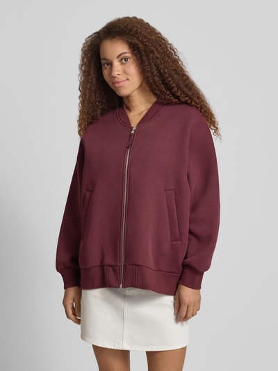 Frauenmodel trägt Bomberjacke mit seitlichen Eingrifftaschen Modell 'Niva' von OH APRIL aus Baumwoll-Mix im Loose-Fit, bordeauxrot, Ganzkörperansicht von vorne.