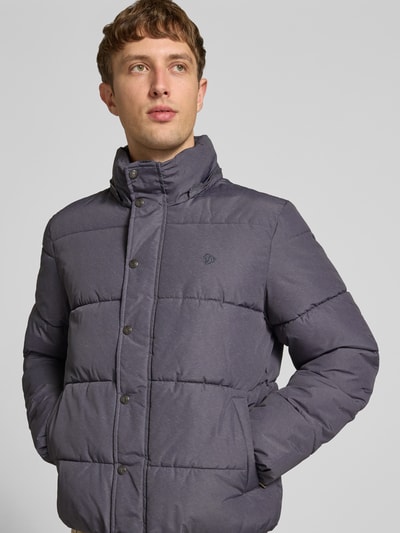 Männermodel trägt Steppjacke mit Kapuze und Reißverschluss von Superdry in Grau, sichtbare Knopfleiste, Nahaufnahme Oberkörper. Regular Fit, Stehkragen, verdeckter Reißverschluss, Rückenlänge 71 cm, Schulterbreite 50 cm, Brustweite 56 cm, Ärmellänge 83 cm.