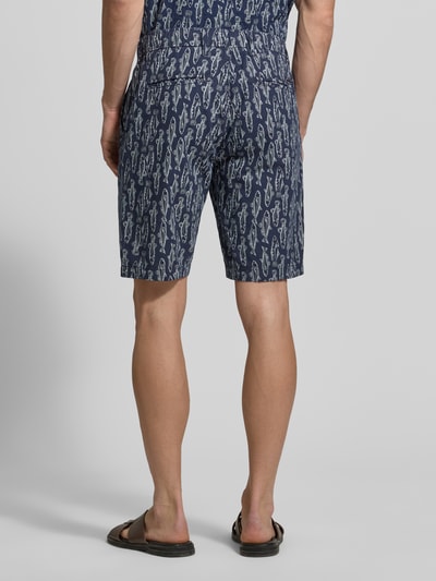Männermodel trägt Chino Shorts mit französischen Eingrifftaschen von Lerros in Dunkelblau mit Fischmuster, Baumwoll-Leinen-Mix, Ganzkörperansicht Rückansicht.