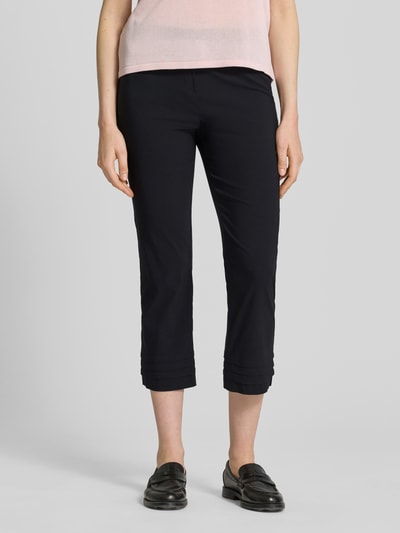 Kobiece model prezentuje spodnie capri z mieszanki wiskozy z dodatkiem streczu STEHMANN Caprihose aus Viskose-Mix Modell 'Ina', czarny kolor, drapowania, krój slim fit, szerokość w rozmiarze 36: 38 cm, długość wewnętrzna nogawki w rozmiarze 36: 59 cm, widok z przodu, zbliżenie na dolną część ciała.