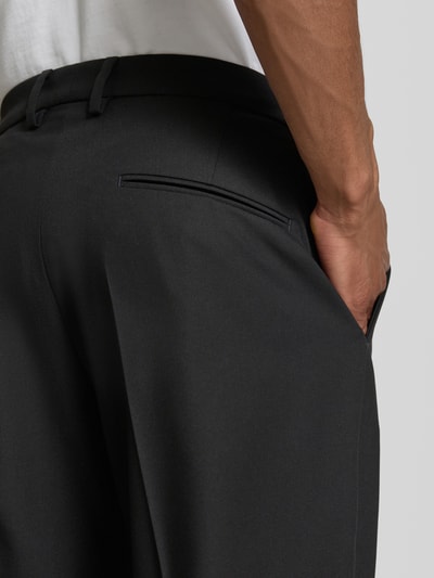 Männermodel trägt Anzughose mit Bügelfalten Modell 'AJEND' von Drykorn in Schwarz, Material-Mix mit Woll-Anteil, Detailaufnahme Rückansicht.
