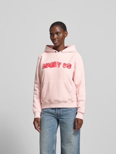 Frauenmodel trägt Oversized Hoodie aus reiner Baumwolle von Kenzo in Rosa mit Statement-Print, Känguru-Tasche, elastische Abschlüsse, Rückenlänge bei Größe S 59 cm, Ganzkörperansicht von vorne.