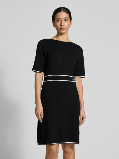 Frauenmodel trägt Regular Fit Kleid aus Viskose-Mix Modell 'Kirla' von JOOP! in Schwarz mit weißen Akzenten, Strick-Optik, Nahaufnahme Oberkörper.