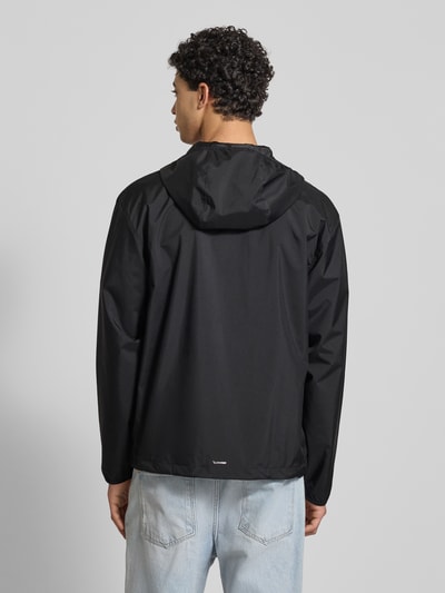 Męski model nosi Jacke mit Kapuze od adidas Originals, czarna, krój regular fit, z kapturem, zamek, kieszenie; widok całej sylwetki z tyłu. Długość pleców w rozmiarze M: 71 cm, szerokość ramion w rozmiarze M: 55 cm, szerokość klatki piersiowej w rozmiarze M: 61 cm, długość rękawa w rozmiarze M: 66 cm.