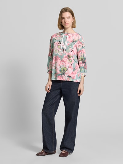 Frauenmodel trägt Sweatshirt mit 3/4-Arm und Kordelzug von Betty Barclay im Loose-Fit, Viskose-Mix mit Statement-Print, Strasssteinbesatz, florale Muster, zarte Pastellfarben, Rundhalsausschnitt mit Kordelzug, Ganzkörperansicht von vorne.