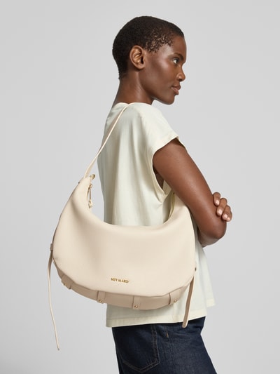 Männermodel trägt Halfmoon Bag mit Label-Detail Modell 'Lifetime Sister' von Hey Marly, beżowa faktura skóry, Szerokość w rozmiarze 1: 33 cm, długość 28 cm, głębokość 13 cm, długość paska 53 cm, zamek błyskawiczny, widok z boku, ujęcie całego ciała