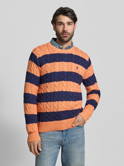 Männermodel trägt Regular Fit Strickpullover aus reiner Baumwolle von Polo Ralph Lauren, dwukolorowy, ścieg warkoczowy, detal z logo, imitacja dzianiny, krój regular fit, okrągły dekolt, długi rękaw, prążkowane zakończenia, z bawełny, Ganzkörperansicht von vorne.