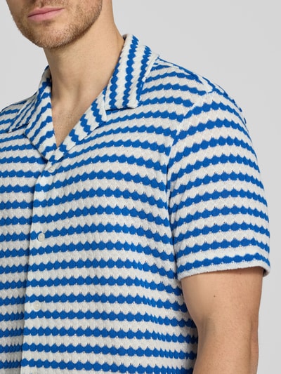 Męski model nosi Relaxed Fit Poloshirt aus Baumwoll-Mix Modell 'DYLAN' von SELECTED HOMME, efekt: wzór na całej powierzchni, krótki rękaw, kołnierz z połami, dekolt w serek, listwa guzikowa, drobny splot, mieszanka bawełny. Nahaufnahme górnej części ciała.