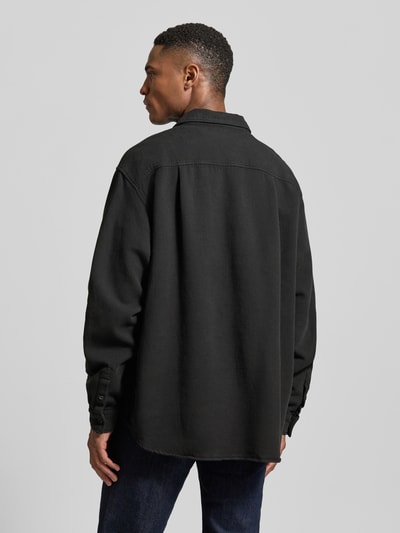 Männermodel trägt Regular Fit Freizeithemd mit Label-Patch von American Vintage in Schwarz, lockerer Schnitt, Rückenansicht, Ganzkörperansicht Rückansicht.