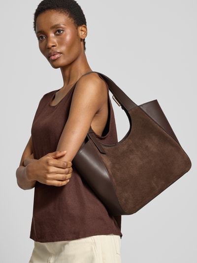 Frauenmodel trägt Tote Bag aus echtem Leder Modell 'Dora' von FURLA in Dunkelbraun, glatte und genarbte Texturen, Nahaufnahme Oberkörper. Hauptfach mit Magnetverschluss, verstellbare Schulterriemen, Innenfach mit Reißverschluss.