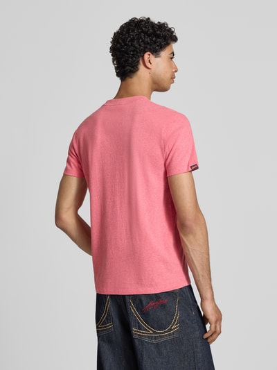 Männermodel trägt Regular Fit T-Shirt mit Logo-Stitching von Superdry in Rosa, kombiniert mit Jeans, Rückenansicht, reine Baumwolle.