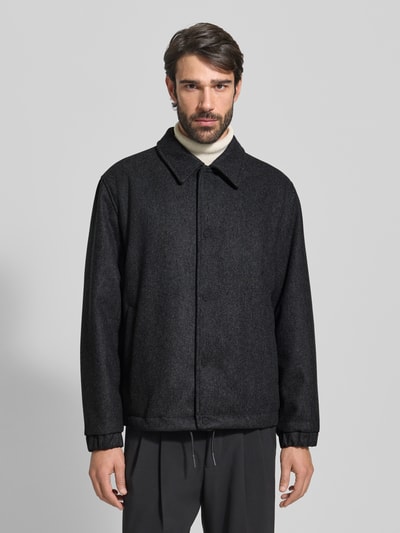 Männermodel trägt Regular Fit Kurzmantel aus Schurwoll-Mix Modell 'BAKS' von HUGO in Melange-Optik, dunkle Farbe, Ganzkörperansicht von vorne.
