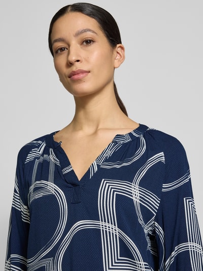 Vrouwenmodel draagt Relaxed Fit Bluse uit pure viscose model 'Cornelia' van ZABAIONE in donkerblauw met witte lijnen, tuniek-hals, 3/4-mouw, afgebiesde mouwuiteinden, elastische zoom, context ruglengte maat S 65 cm, mouwlengte 29 cm, close-up bovenlichaam.