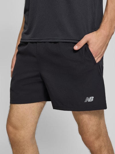 Männermodel trägt czarne szorty z elastycznym pasem i logo Shorts mit elastischem Bund und Logo von New Balance, krój regular fit, tunel, szerokość w rozmiarze M: 39 cm, długość wewnętrzna nogawki w rozmiarze M: 12 cm, Nahaufnahme bioder i ud z przodu