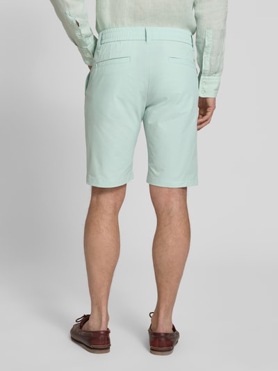 Männermodel trägt Tapered Fit Bermuda mit Kordelzug Modell 'CHINO' von BOSS Orange in Mint mit Allover-Muster, Ganzkörperansicht Rückansicht.