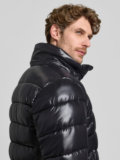 Männermodel trägt schwarze, glänzende Steppjacke mit abnehmbarer Kapuze Modell 'FLORIAN' von Save The Duck, Nahaufnahme Oberkörper. Rückenlänge, Schulterbreite, Brustweite und Ärmellänge laut Größe M.