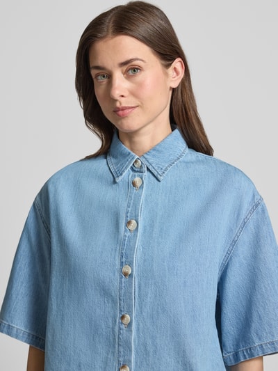 Vrouwenmodel draagt Relaxed Fit Jeansbluse aus reiner Baumwolle van s.Oliver RED LABEL in lichtblauw denim, korte mouwen, katoenen twill, label patch, V-hals, knoopsluiting, hemdblousekraag, rugpas met Cacharel plooi, detailopname bovenlichaam