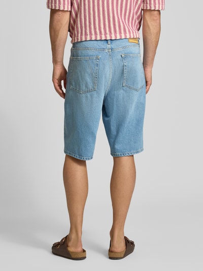Männermodel trägt Loose Fit Jeansshorts aus Lyocell-Baumwoll-Mix Modell 'BAGGY HEMP BLEND' von Armedangels in heller Denim-Optik, 5-Pocket-Design, Label Patch, Ganzkörperansicht Rückansicht.