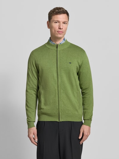 Männermodel trägt grüne Strickjacke mit Reißverschluss von Fynch-Hatton, Reine Baumwolle, Regular-Fit, gerippte Abschlüsse, Stehkragen, Label-Stitching, Eingrifftaschen, Rückenlänge 67 cm, Ärmellänge 69 cm, Ganzkörperansicht von vorne.