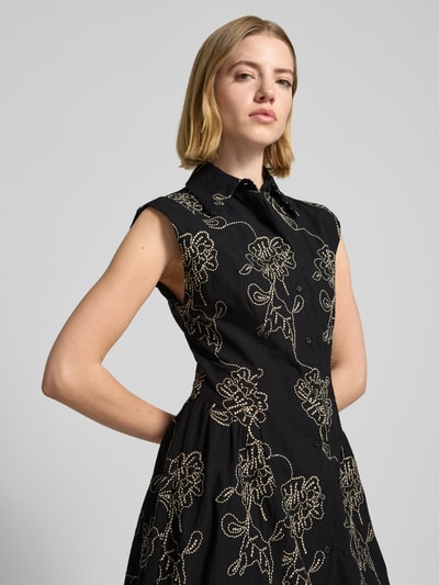 Frauenmodel trägt Hemdblusenkleid im Allover-Look Modell 'CATARINA' von Mango aus Baumwoll-Mix in Schwarz mit floralen Mustern, Nahaufnahme Oberkörper. Rückenlänge bei Größe S: 129 cm, Brustweite bei Größe S: 44 cm, A-Linie, Midikleid.
