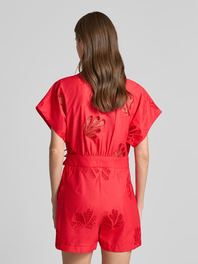 Frauenmodel trägt Jumpsuit in Wickel-Optik Modell 'TRACY' von SUNCOO PARIS in Rot mit Lochstickerei und Bindegürtel, Ganzkörperansicht Rückansicht.