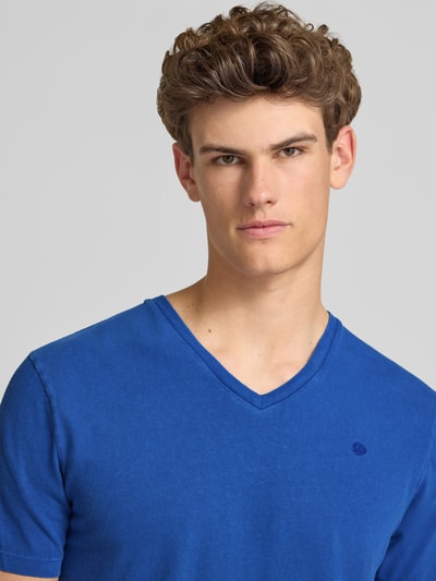 Männermodel trägt T-Shirt aus Baumwoll-Leinen-Mix mit V-Ausschnitt von Superdry in Blau, Regular-Fit, Stitching, Nahaufnahme Oberkörper. Rückenlänge bei Größe M: 68 cm.
