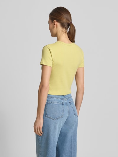 Frauenmodel trägt Slim Fit T-Shirt aus Baumwoll-Mix Modell 'DELANOR' von HUGO in Gelb, Optik: Unifarben, Cropped, Logo-Stitching, Ganzkörperansicht Rückansicht.