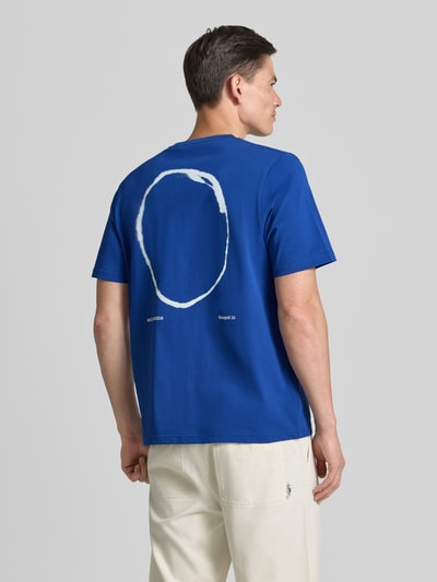 Männermodel trägt T-Shirt mit rückseitigem Motiv-Print Modell 'Bobby' von Wood Wood in Blau, Baumwolle, Regular Fit, Ganzkörperansicht Rückansicht.