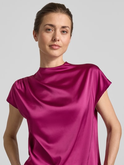 Frauenmodel trägt Blusenshirt mit Rundhalsausschnitt und Kappärmeln von Zero aus Material-Mix mit Stretch-Anteil, gerader Schnitt, magentafarben, glatte Textur, Rückenlänge bei Größe 36: 56 cm, Nahaufnahme Oberkörper.