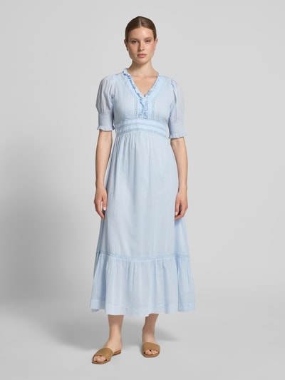 Frauenmodel trägt hellblaues Damen Midikleid mit Rüschen und Häkelspitze Modell 'Alvina' von Neo Noir aus Reine Baumwolle, taillierter Schnitt, V-Ausschnitt, Smok-Detail an den Ärmeln, Ganzkörperansicht von vorne.