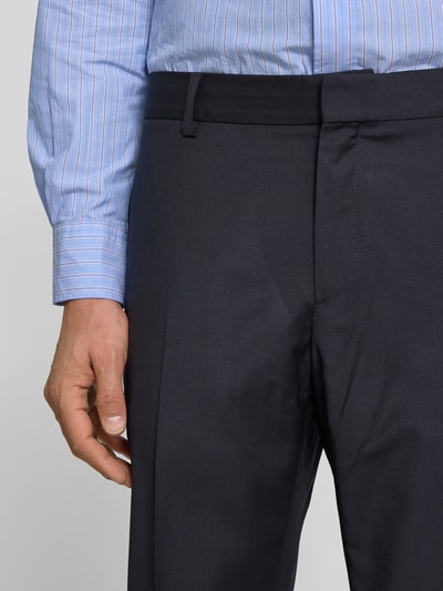Männermodel trägt Slim Fit Anzughose aus Woll-Mix von Filippa K, dunkelblau, Haken- und Reißverschluss, Eingriff- und Gesäßtaschen, Bundfalten, Nahaufnahme Oberkörper.