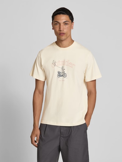 Männermodel trägt Regular Fit T-Shirt mit Motiv-Print von Forét, helle Reine Baumwolle, Logo-Print, Rundhalsausschnitt, Ganzkörperansicht von vorne. Rückenlänge bei Größe M: 67 cm.